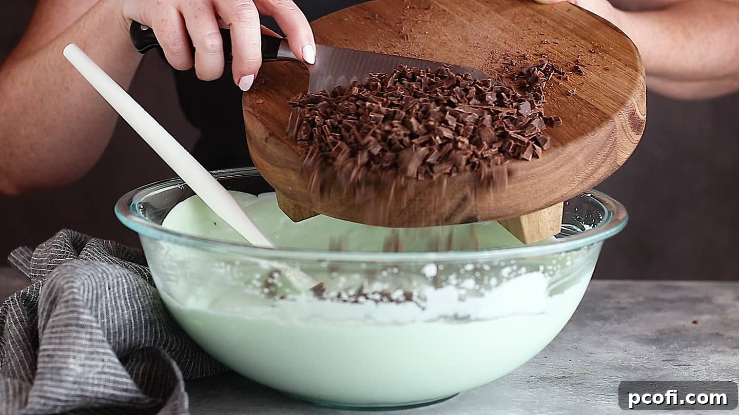 Adding perfectly chopped chocolate to the vibrant mint ice cream base, ensuring a delightful chocolate distribution.