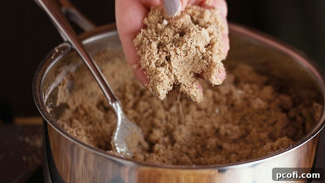 A close-up shot of a hand gently holding a handful of cinnamon streusel crumb topping, showcasing its delightful texture and rich color.