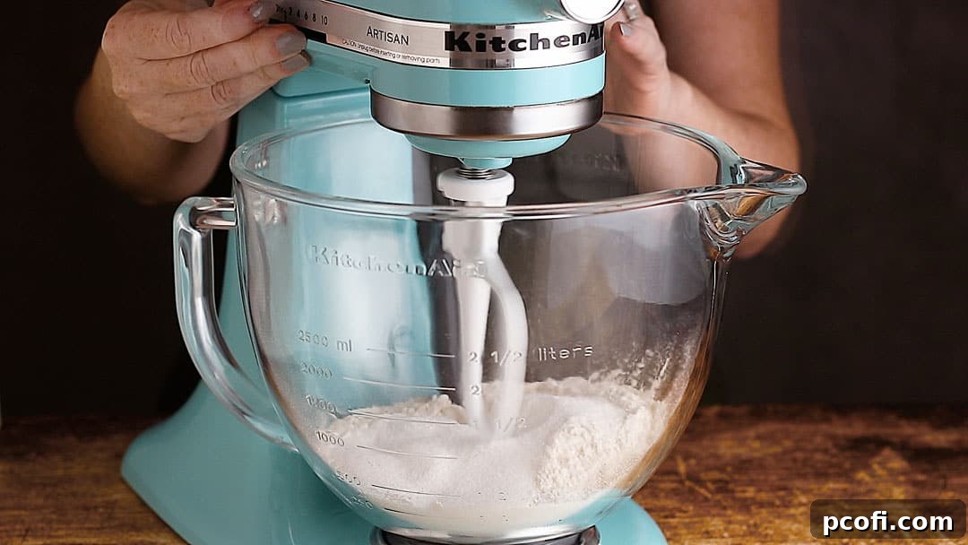 A stand mixer is seen stirring dry ingredients together, ensuring they are well combined before the wet ingredients are introduced.