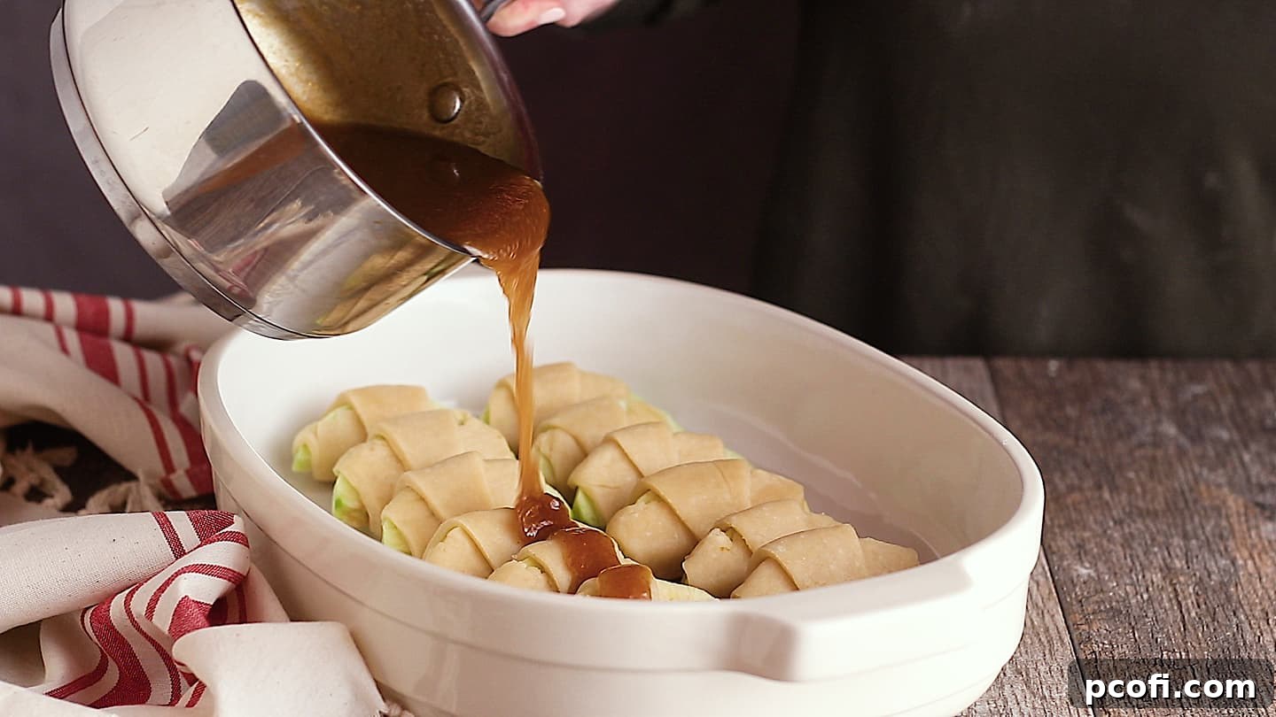 Pouring brown sugar sauce over homemade apple dumplings, creating a luscious glaze.