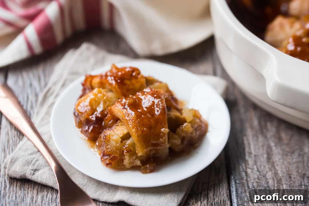 Baked apple dumplings on a small white plate with a copper fork and a red striped dish towel. A delicious dessert ready to be served.