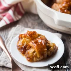 Two apple dumplings on a white plate with a copper fork and a linen napkin in the background.