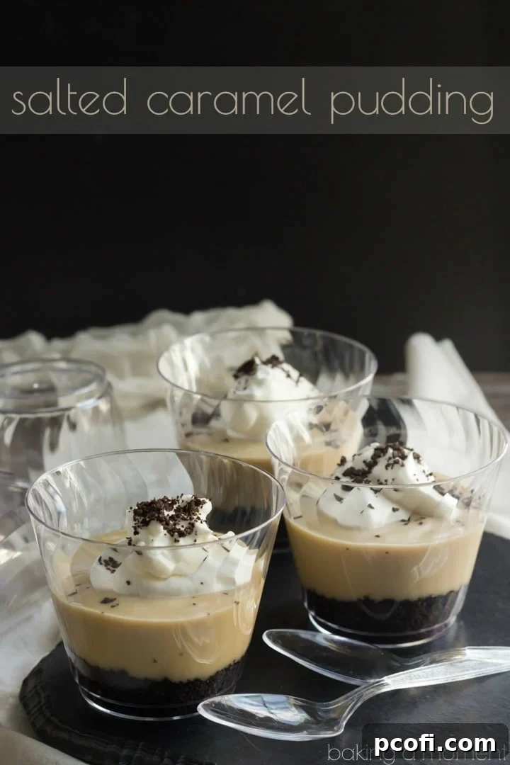 Close-up of a glass of salted caramel pudding, showing the distinct layers of creamy caramel, dark cookie crumbs, and fluffy whipped cream.