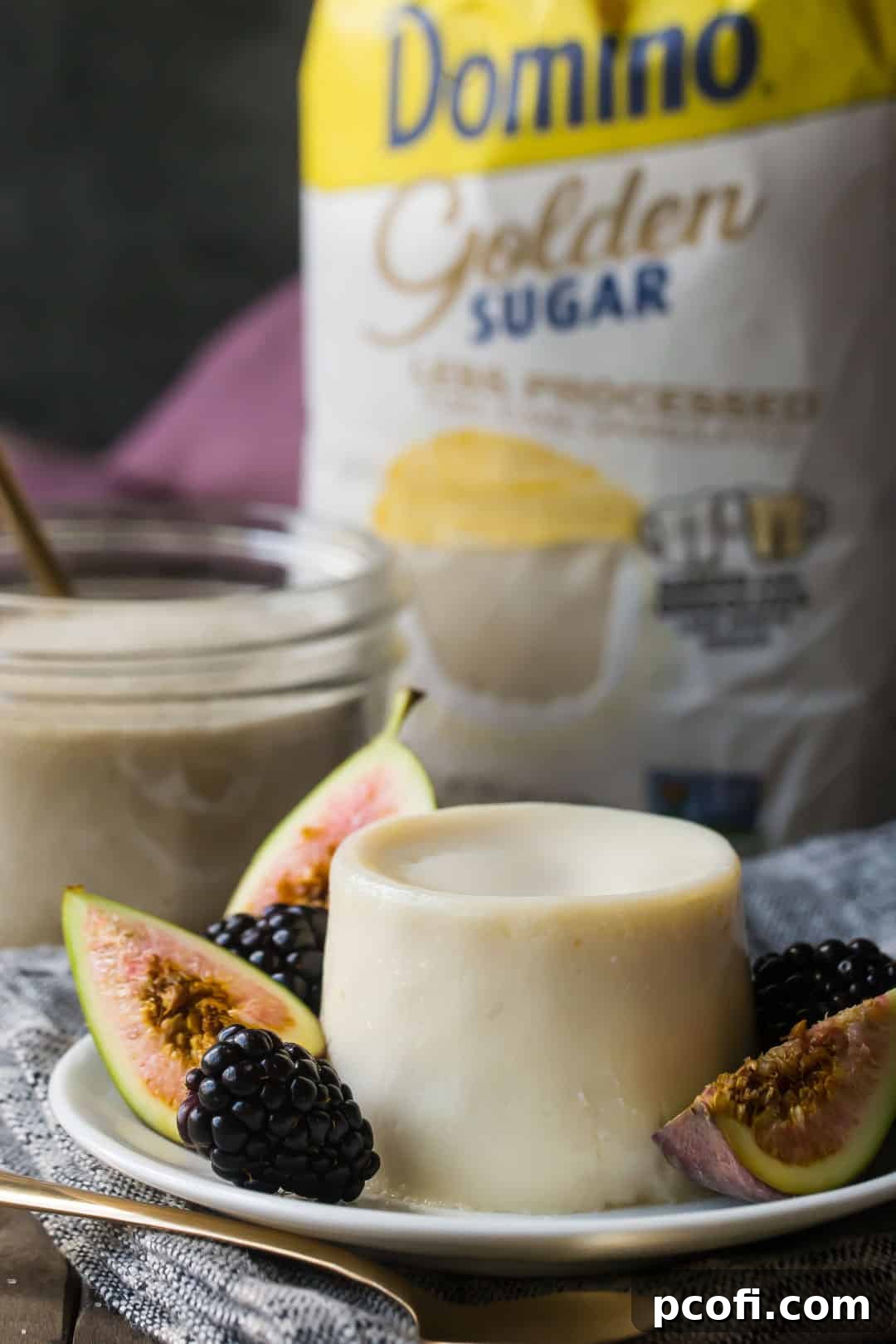 Vanilla panna cotta plated with fresh fruit, with golden sugar in the background.