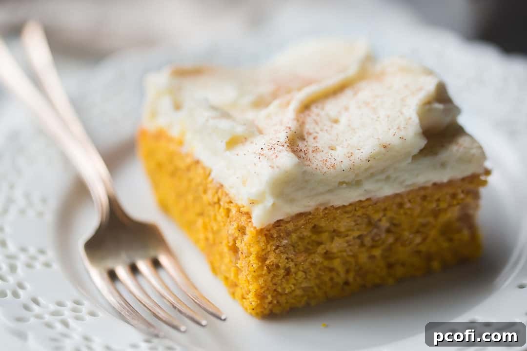 Close up image of a square of moist homemade pumpkin cake on a white plate with a silver fork.