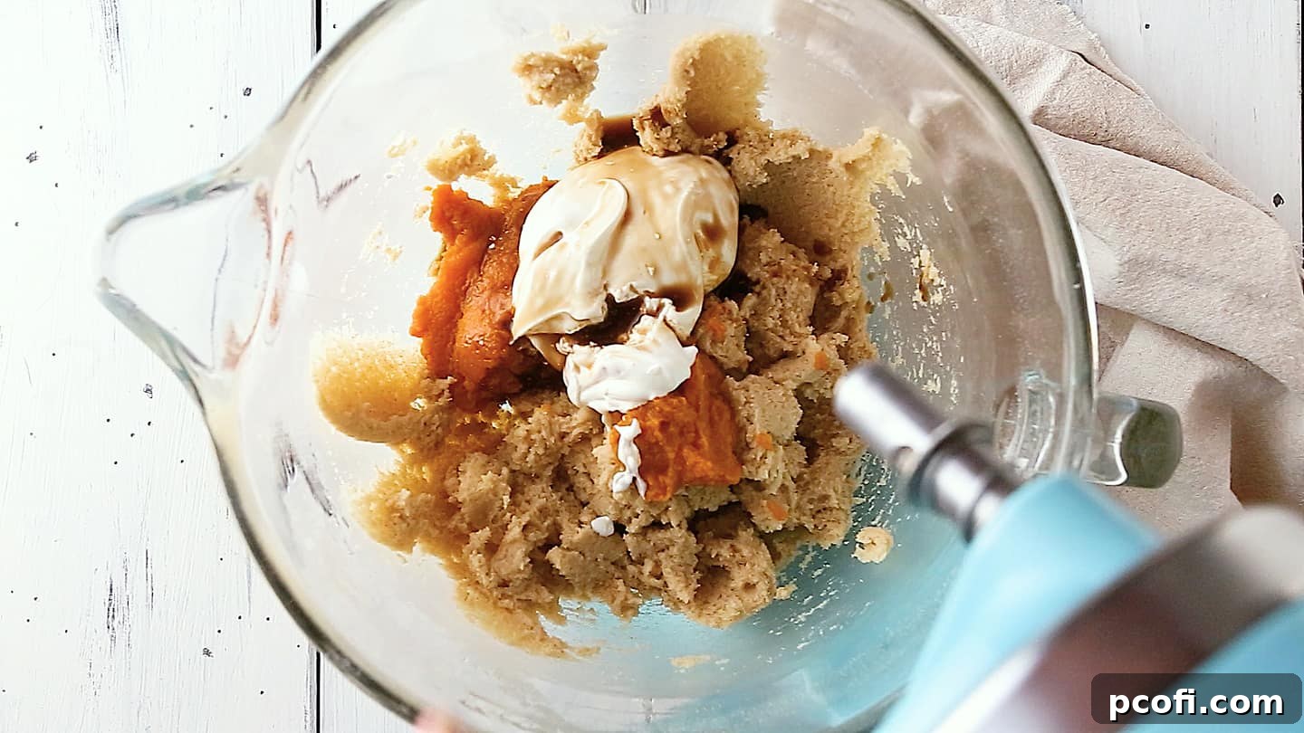 Adding pumpkin, sour cream, and vanilla to pumpkin cake.