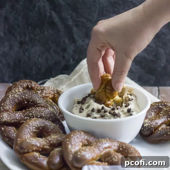 Homemade soft pretzels stuffed with creamy peanut butter, served with a malted vanilla cream cheese dip featuring banana and chocolate chips – an outrageous game day treat for sharing.