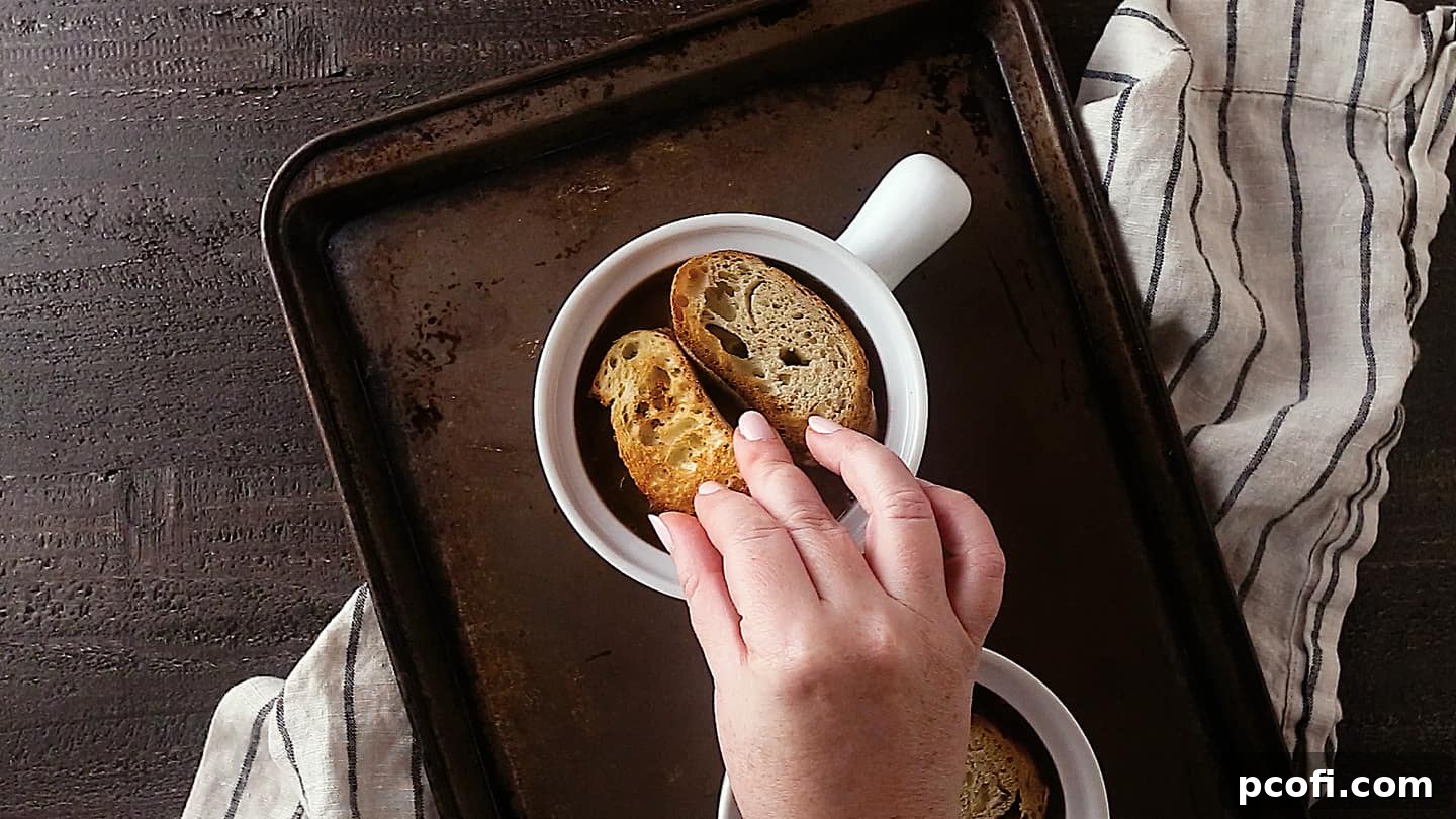 Topping French onion soup with slices of toasted French bread.