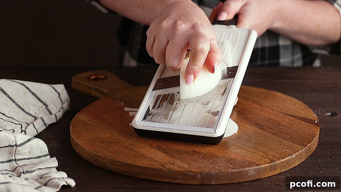 Slicing onions on a mandoline slicer for French onion soup.