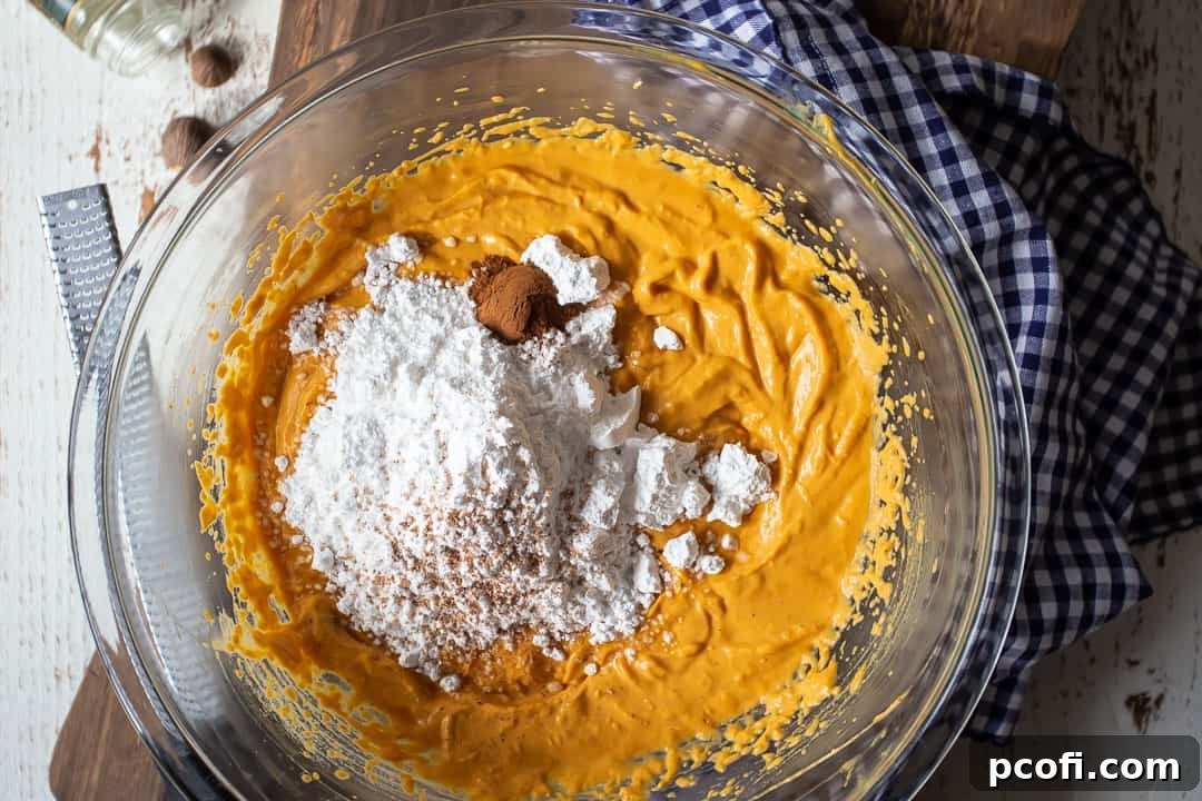 Incorporating powdered sugar and aromatic spices like cinnamon and nutmeg into the pumpkin gooey butter cake filling, enhancing its holiday flavor profile.