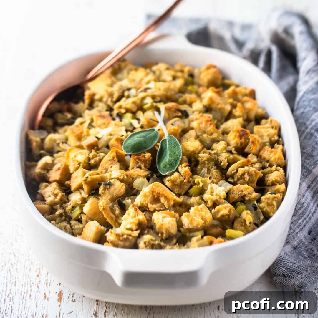 Thanksgiving stuffing recipe baked in a white casserole dish with fresh sage and a gray cloth in the background.