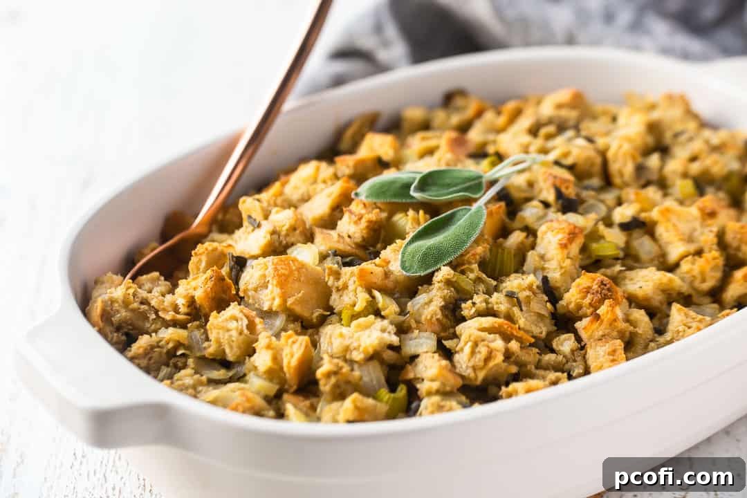 Dressing for Thanksgiving, baked in a white dish with fresh sage and a rose gold serving spoon.
