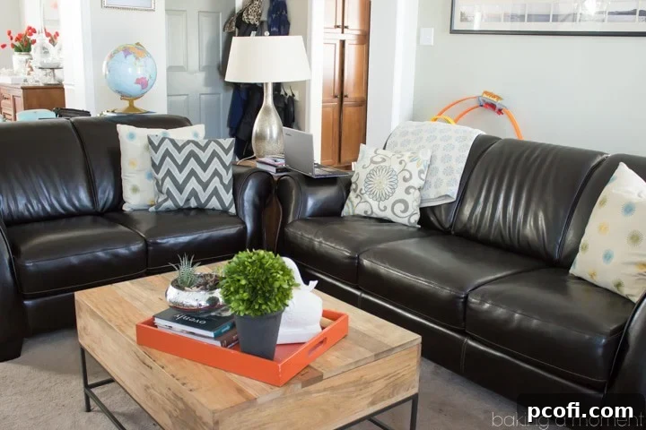 Before image of a living room with dark leather sofas and child's toys