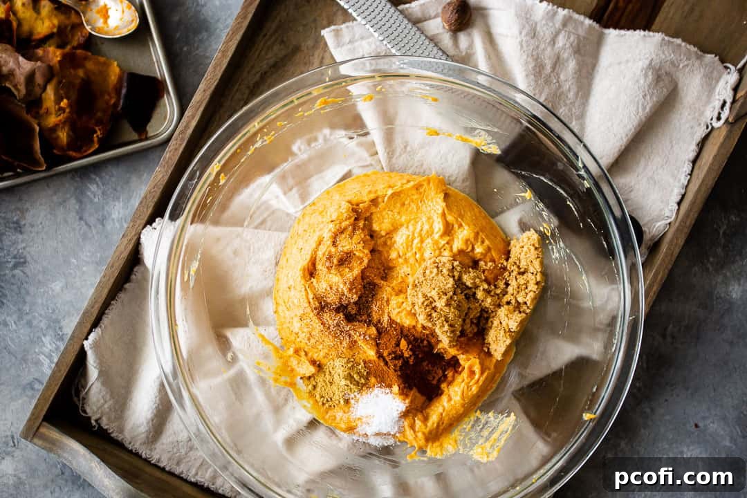 The smooth sweet potato mixture in a glass bowl, now enriched with brown sugar and a medley of warm spices, ready for the final additions to the pie filling.