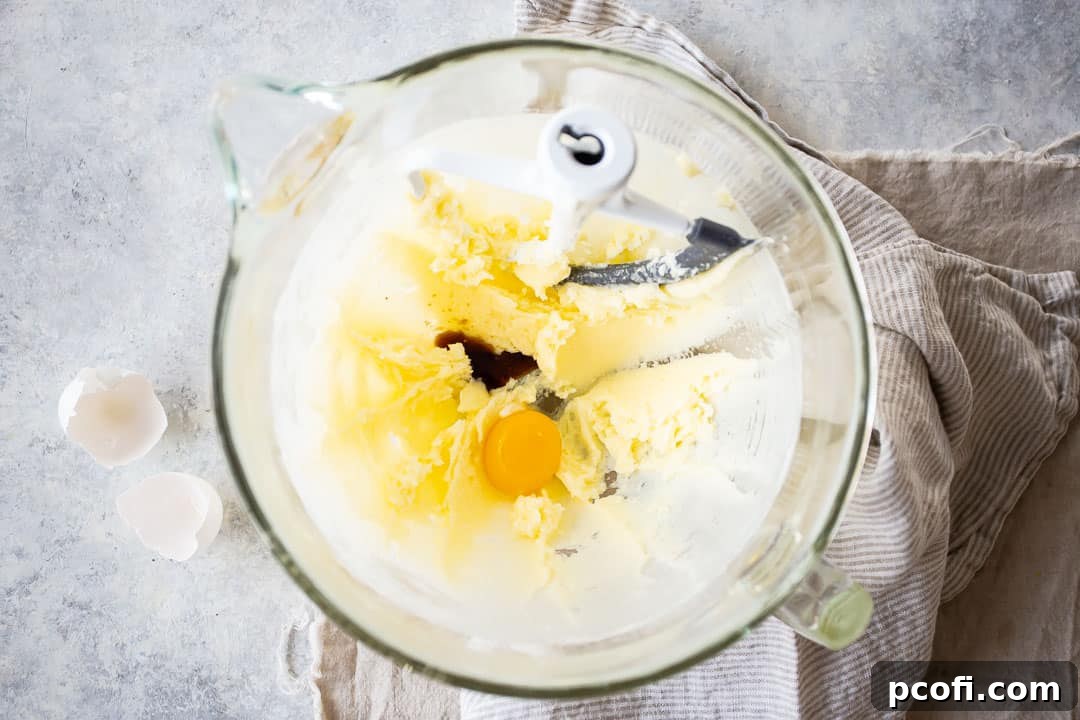 Adding a single egg yolk and a splash of pure vanilla extract to the creamy butter and sugar mixture for pecan sandies.