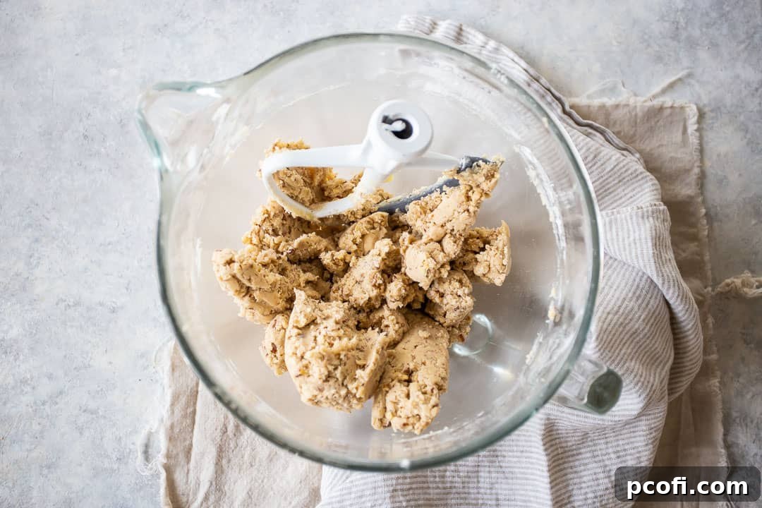 The finished pecan sandies cookie dough, perfectly mixed and ready for shaping, rests in a large glass mixing bowl.