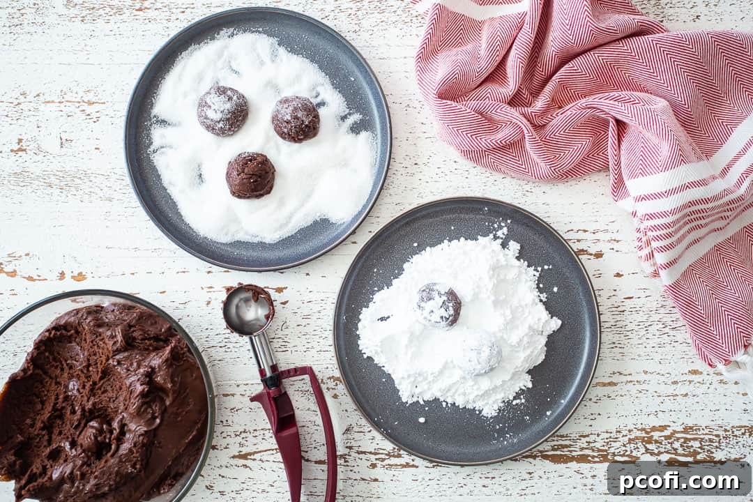 Rolling chocolate crinkle cookies in granulated sugar and then powdered sugar to achieve the classic coating.