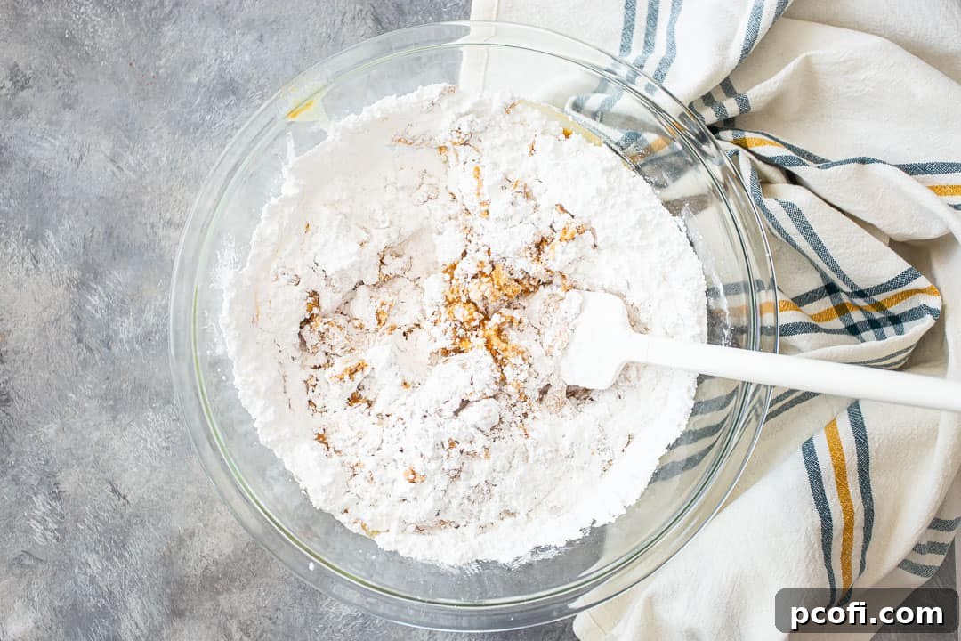 Carefully adding powdered sugar, one cup at a time, to the hot peanut butter mixture for microwave fudge.