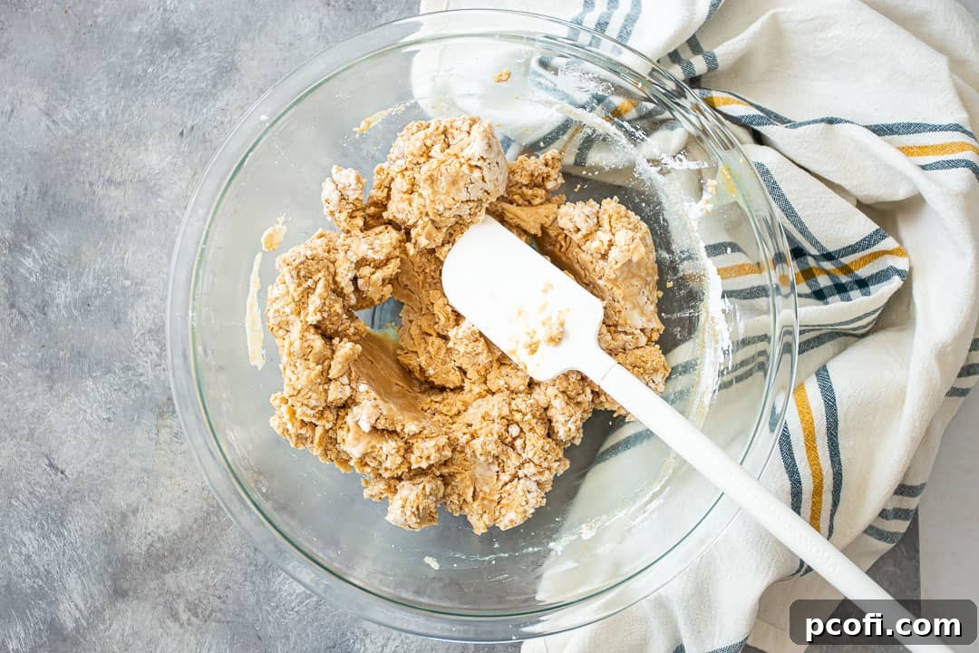 Mixing the stiff peanut butter fudge mixture in a large glass bowl, showcasing its dense texture.