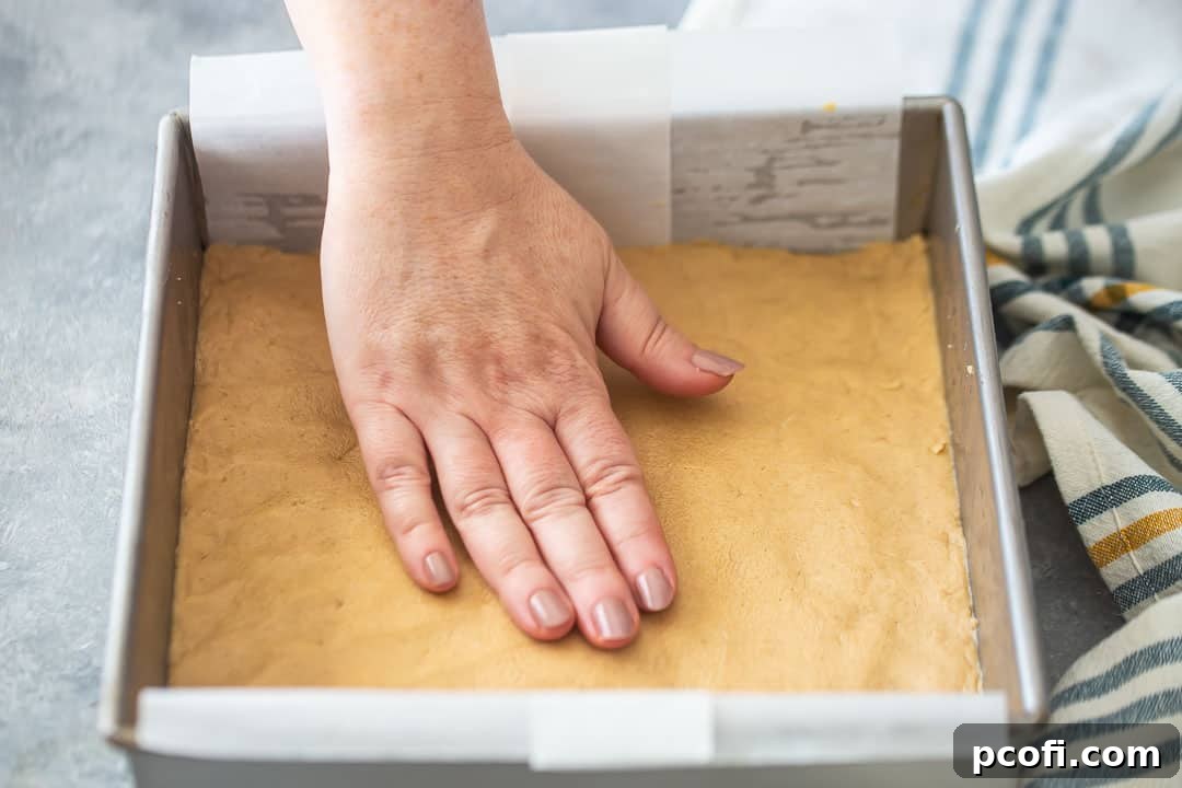 Finishing touch: chopped peanuts sprinkled over the top of peanut butter fudge in an 8x8 pan, ready to cool.