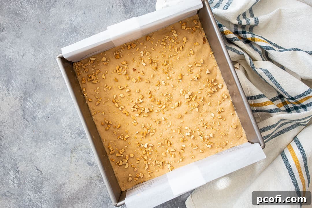 Close-up of the smooth, firm peanut butter fudge in the pan, garnished with chopped peanuts, ready for slicing.