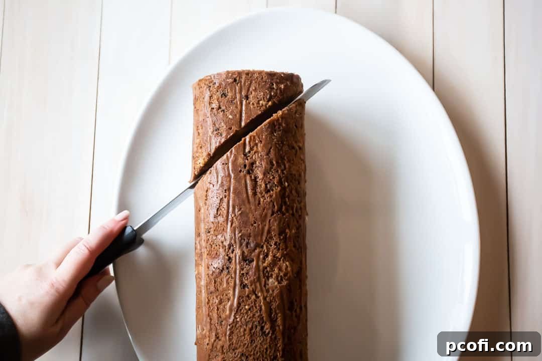 Carefully trimming a Buche de Noel cake with a serrated knife to create a realistic log shape, ready for frosting and garnishing.