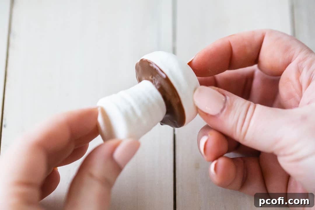Attaching meringue mushroom stems to their caps with melted chocolate, creating charming edible forest decorations for a Yule Log cake.