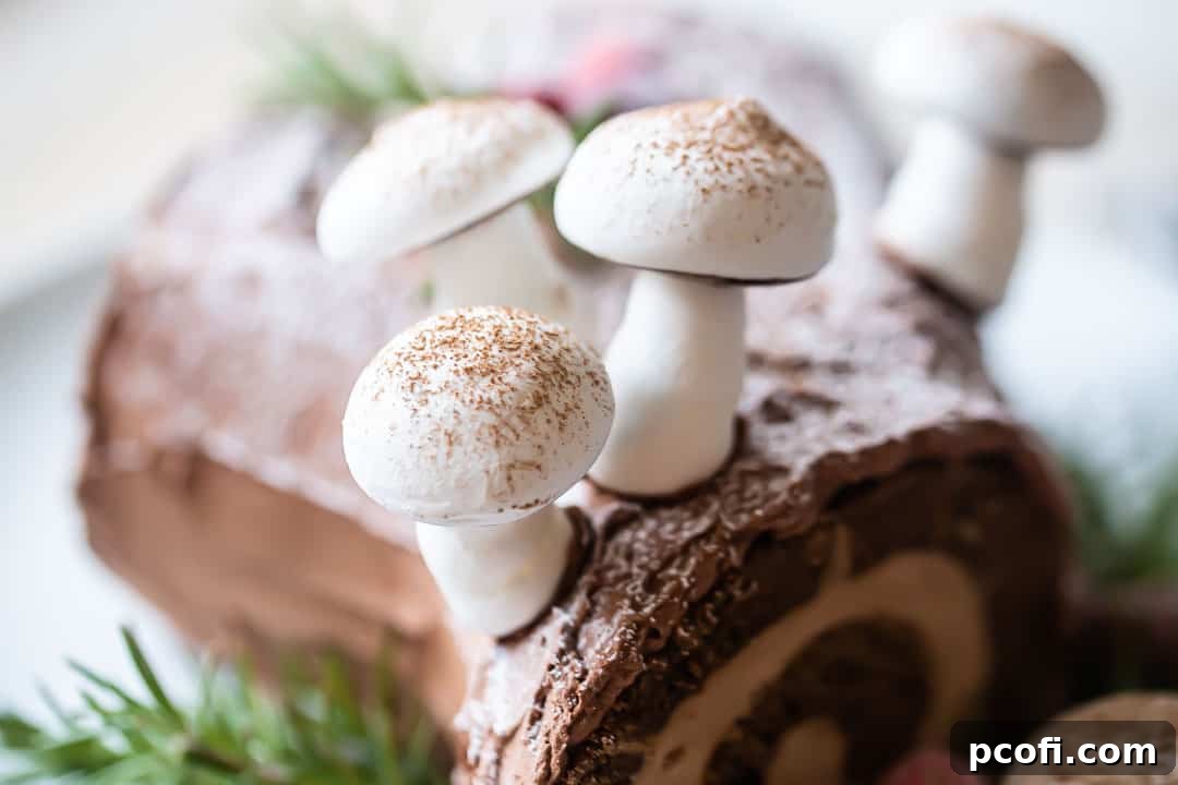 Close-up image of beautifully arranged meringue mushrooms on a chocolate yule log cake, dusted with cocoa powder for a realistic forest look.