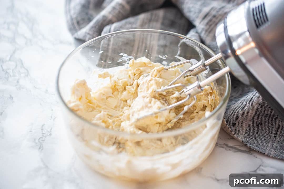 Mixing crab dip cream cheese base in a bowl with an electric mixer.