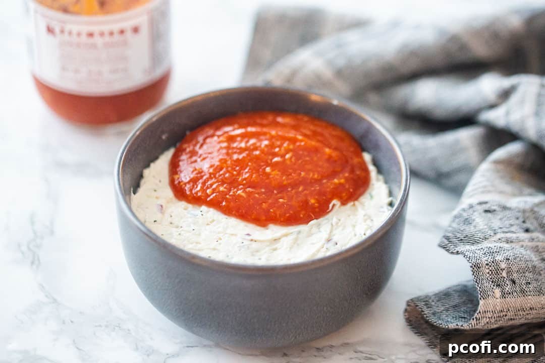 Cold crab dip in a serving bowl with cocktail sauce on top.