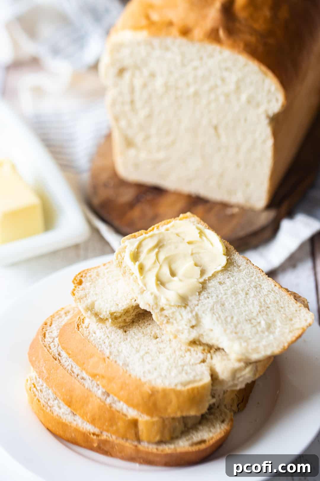 Perfectly sliced soft white sandwich bread, stacked neatly on a white plate, highlighting its tender crumb and inviting texture.