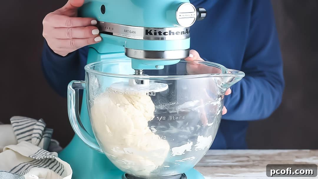 Soft white bread dough forming a cohesive ball, cleanly separating from the sides of the mixing bowl, indicating ideal flour consistency.