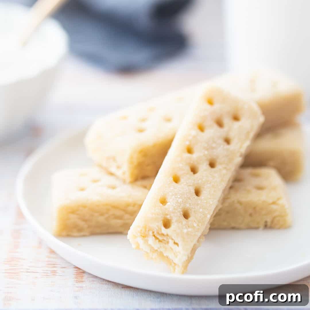 Classic shortbread cookies arranged beautifully on a white plate with a sugar bowl in the background, showcasing their golden edges.