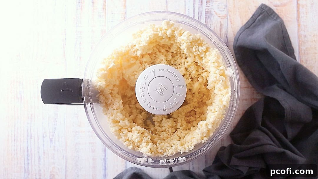 Granulated sugar, kosher salt, and cold unsalted butter are ready in the bowl of a food processor for mixing.