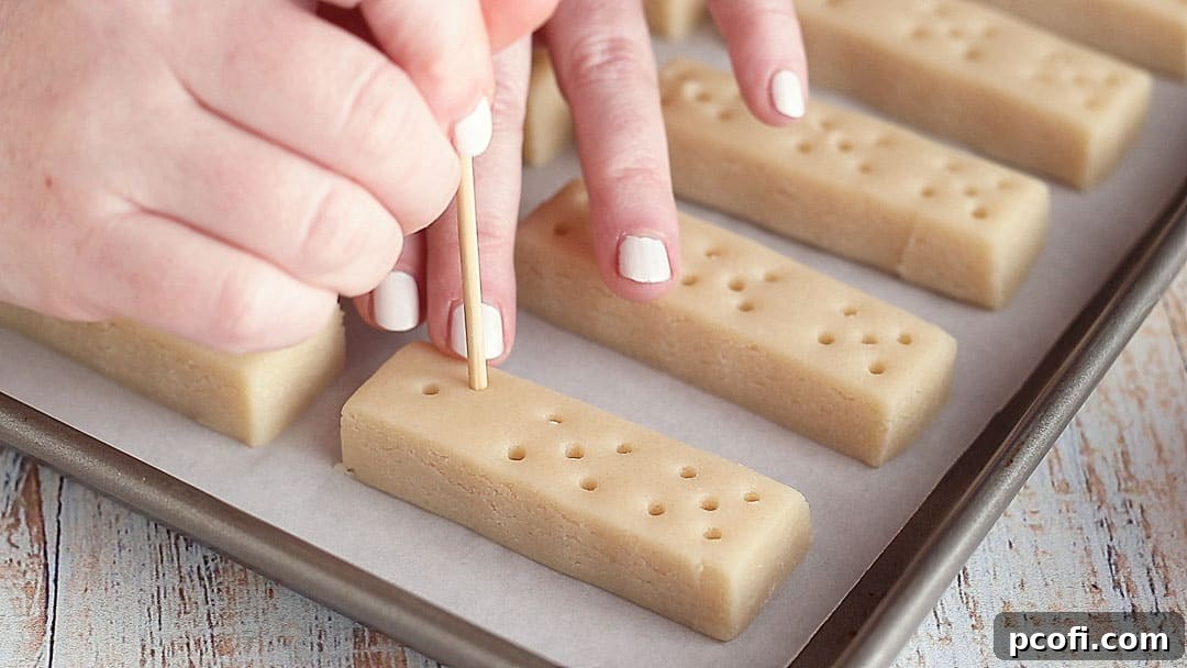 A bamboo skewer being used to dock shortbread cookies, creating their distinctive patterned holes.