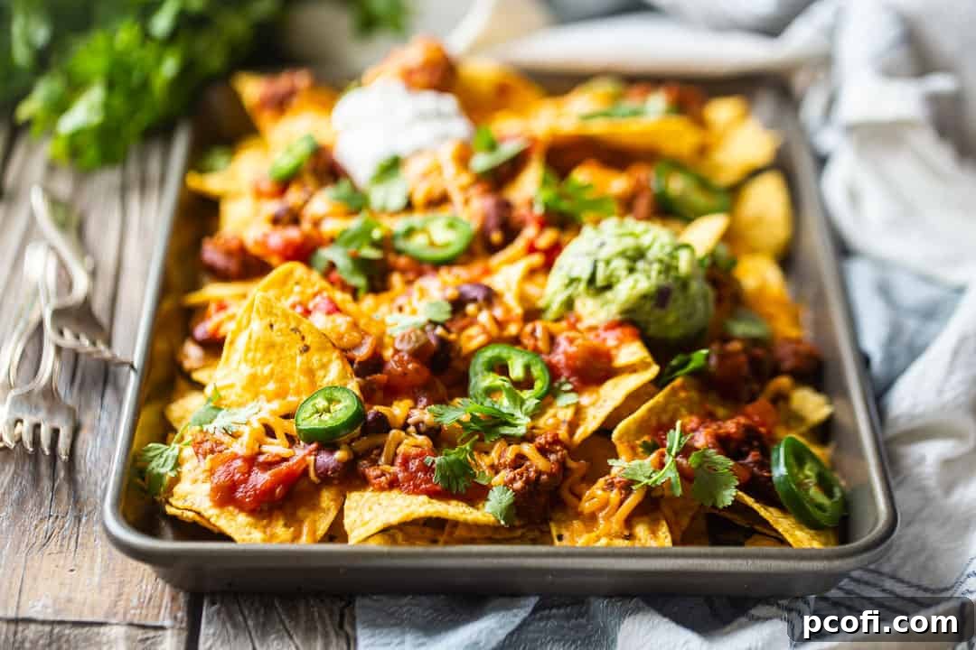 Homemade nachos recipe, prepared on a sheet pan with guacamole and sour cream.