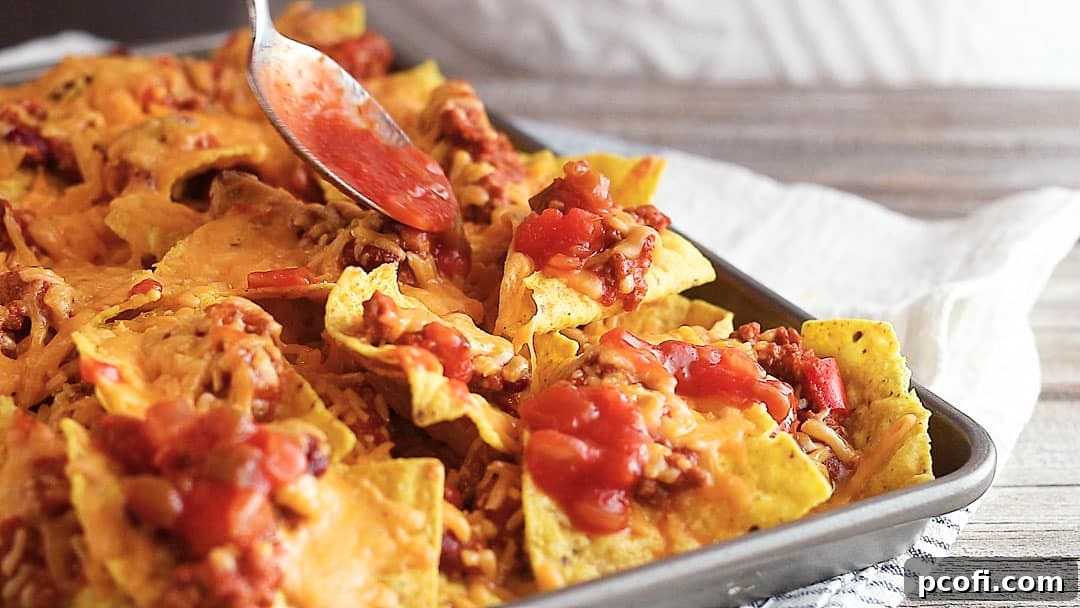 Spooning salsa over sheet pan nachos recipe.