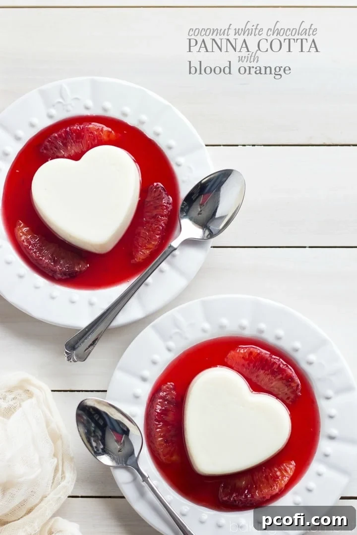 Close-up of heart-shaped Coconut White Chocolate Panna Cotta, drizzled with crimson blood orange sauce and garnished with segments.