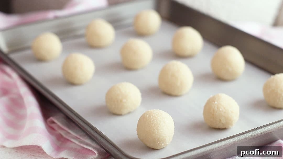 Thumbprint cookie dough balls on a baking sheet.