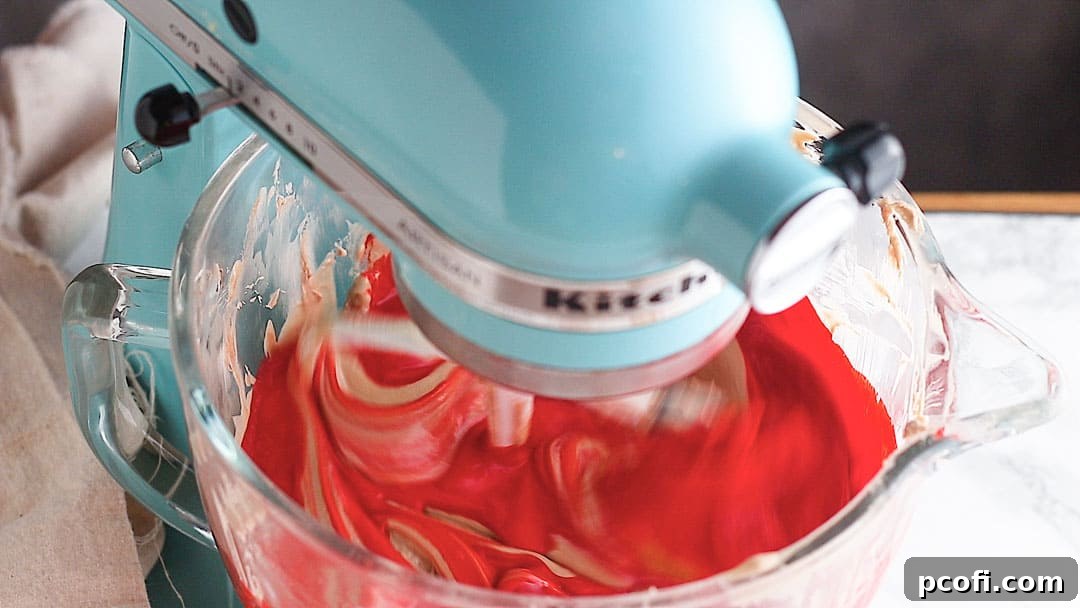 Red velvet cheesecake batter in a blue stand mixer.