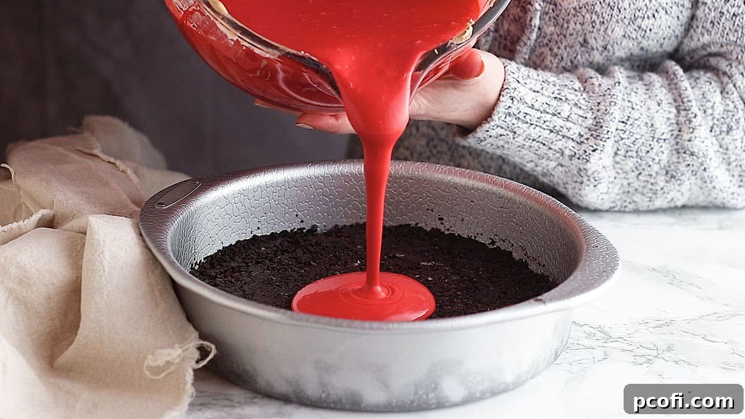 Pouring red velvet cheesecake batter over Oreo crust.