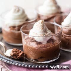 Small glass bowls of chocolate mousse with whipped cream on an antique silver tray.