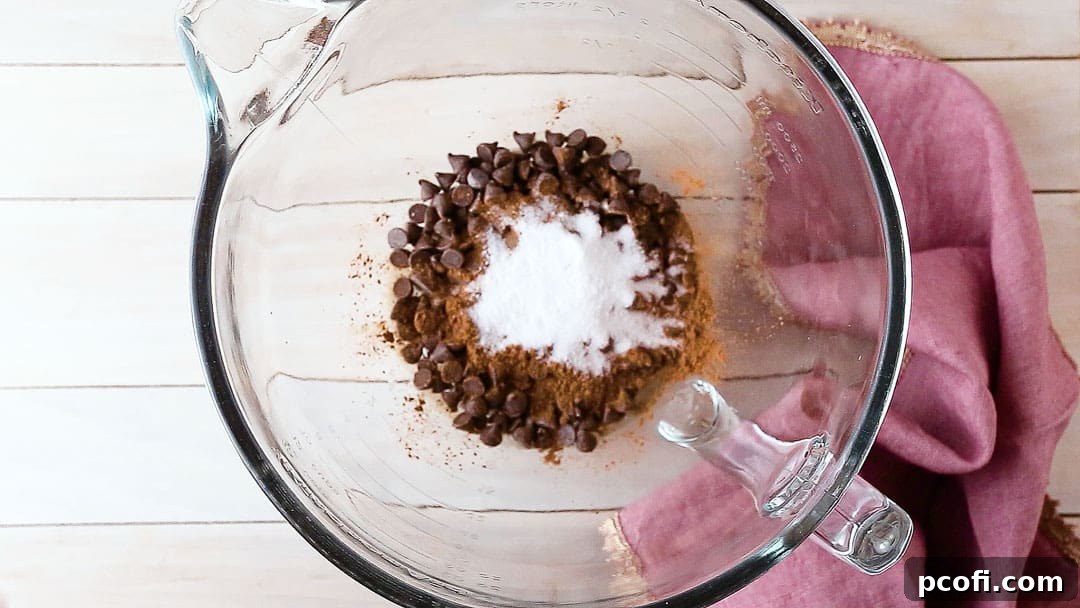 Chocolate mousse ingredients (chocolate chips, water, cocoa, sugar, salt) in a large glass mixing bowl, ready for melting.