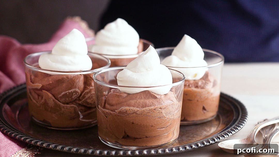 Topping individual chocolate mousse servings with a generous dollop of freshly whipped cream for an added touch of elegance and sweetness.