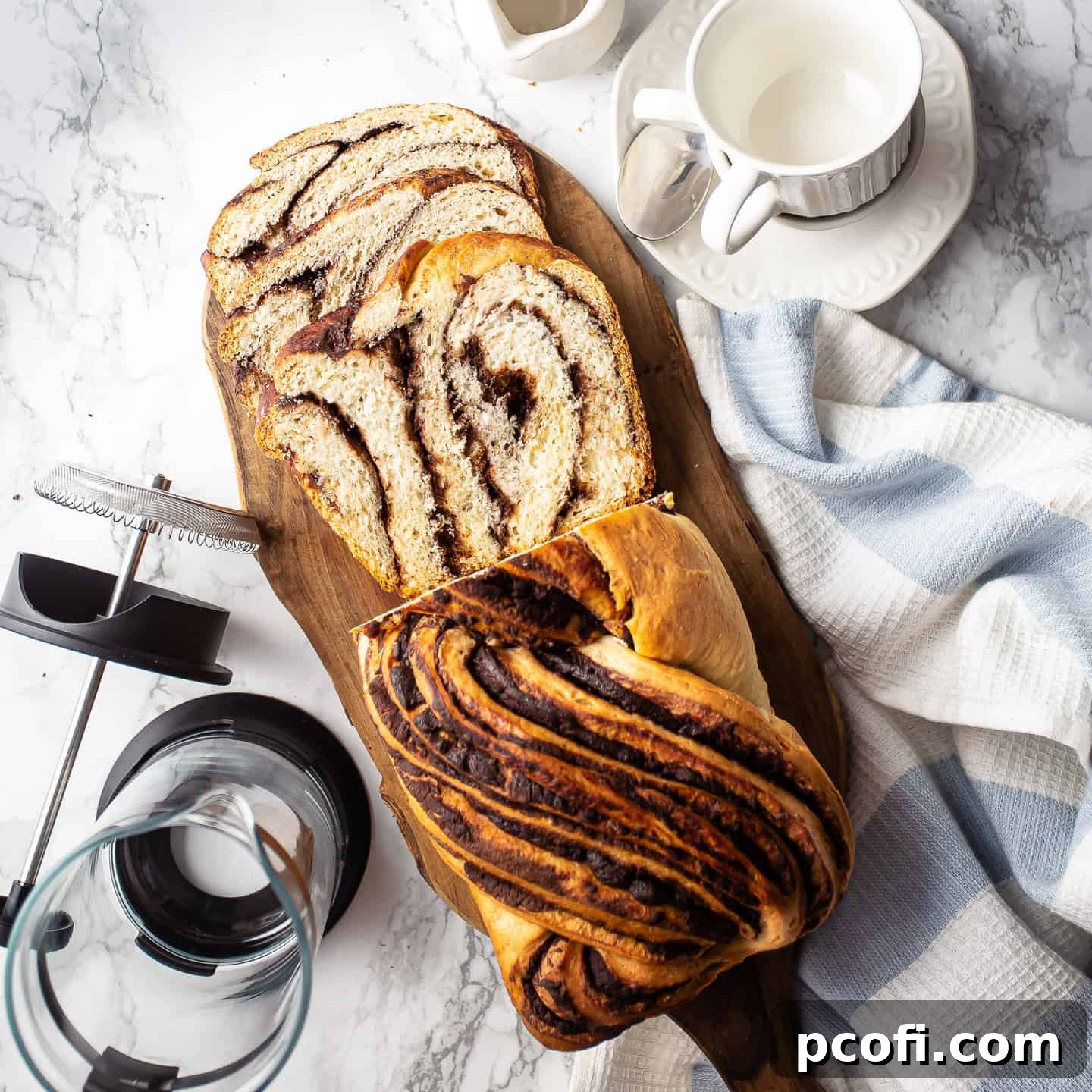 Homemade chocolate babka on a wooden board with a French press coffee pot.