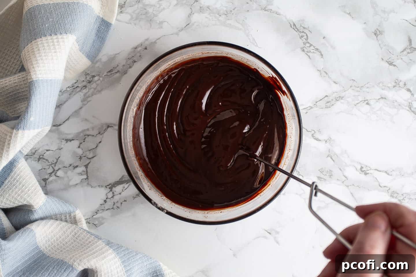 Freshly made ganache being whisked together in a glass bowl.