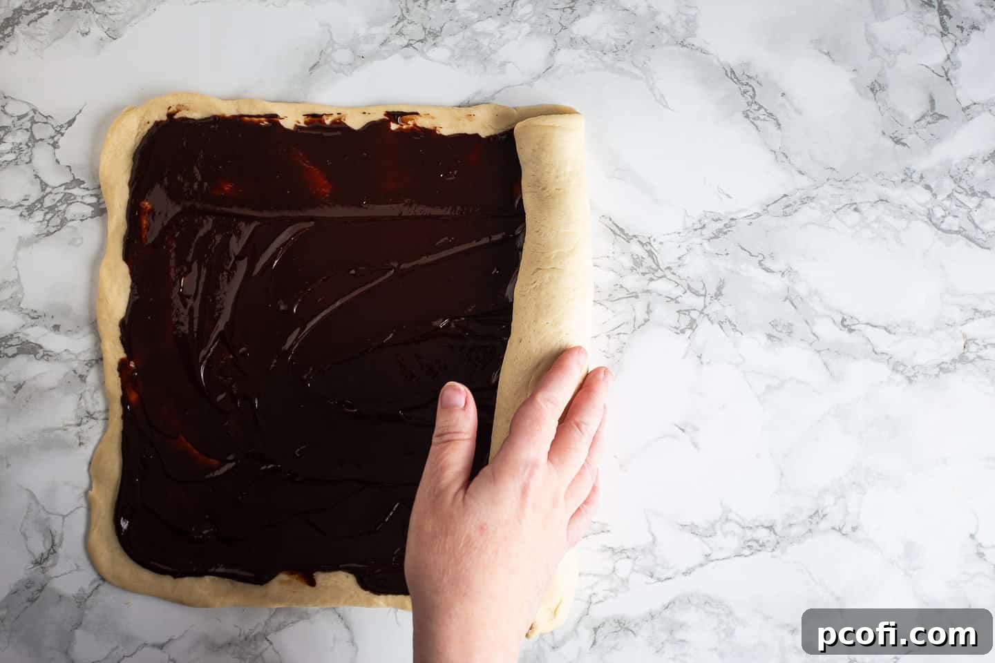 Rolling chocolate babka into a tight log.
