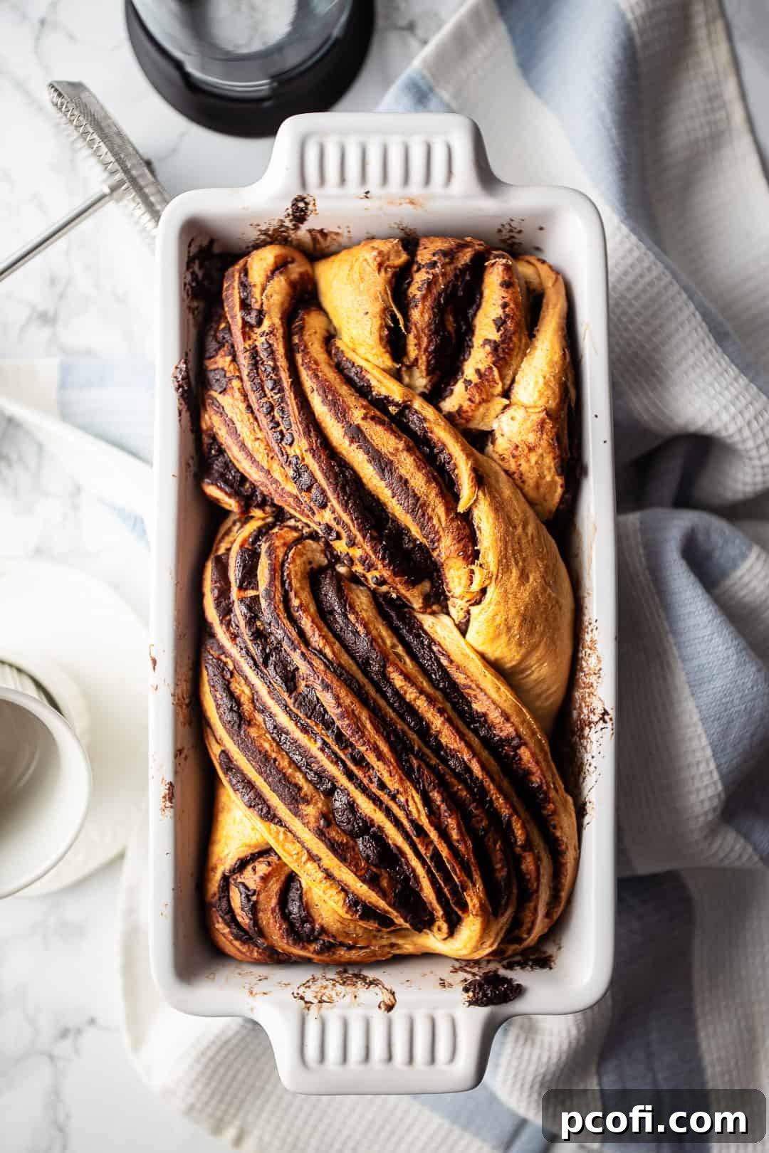 Babka chocolate bread presented on a white marble surface.