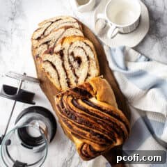 Homemade chocolate babka on a wooden board with a French press coffee pot.