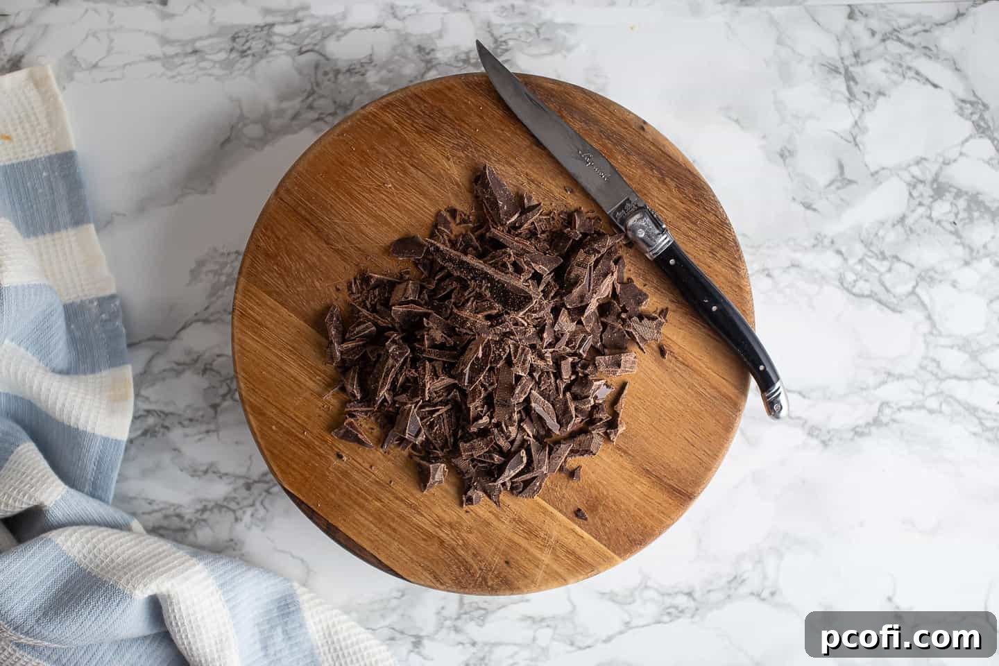 Chopped chocolate on a wooden cutting board.